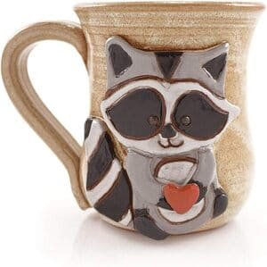 stoneware coffee mug with cartoonish raccoon holding a heart